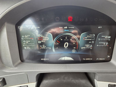 Dashboard display of a Kenworth truck showing digital gauges including center speedometer at 0 mph, left and right auxiliary gauges, warning icons, and a high-tech digital cockpit.