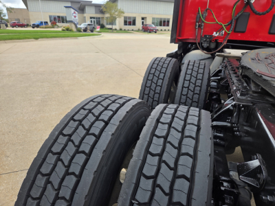 Kenworth T680 truck chassis showing dual rear axles with tires and suspension; part of the cab and wiring visible.
