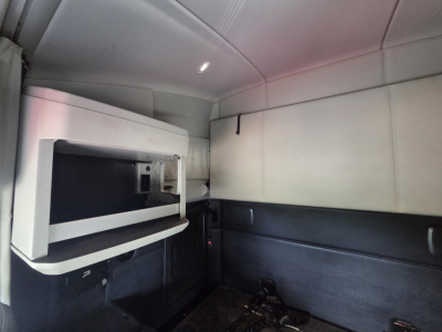 Kenworth truck sleeper cab interior showing a mounted microwave unit and sidewall panels.