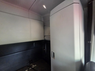 Kenworth T680 sleeper cab interior showing storage cabinet and side panel in a light-colored cabin