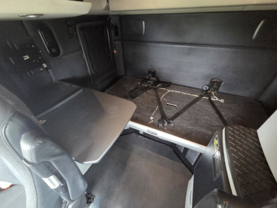 Kenworth T680 cab interior showing sleeper area with folding table and bed mounting rails.