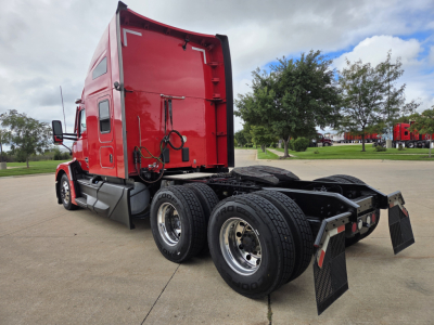 Kenworth T680 sleeper tractor with red cab, rear view showing dual rear axles and chassis, no visible text.