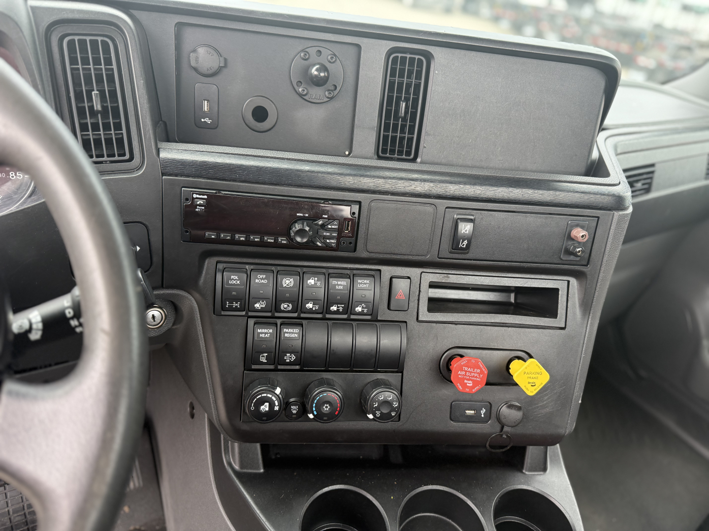 Cab dashboard of a 2021 International LT625 truck showing control panel, air vent, and knobs. Includes radio, climate controls, and engine start/stop symbols.