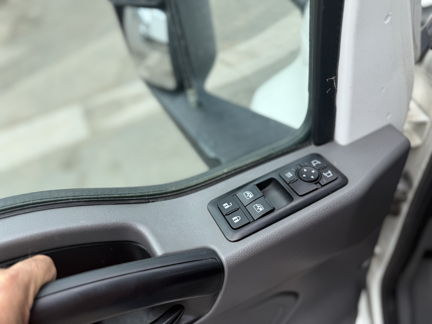 Truck cab interior door panel with window controls and mirror adjustment buttons.