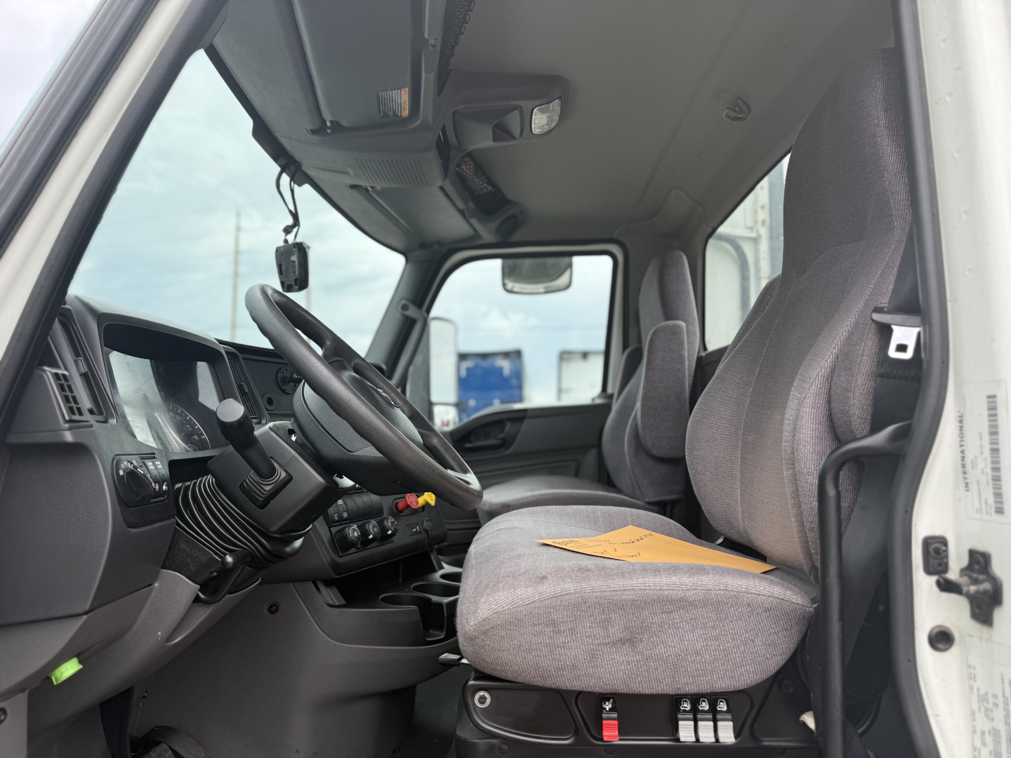 Interior of a 2021 International LT625 daycab showing the driver's seat and steering wheel with instrumentation and dash controls.