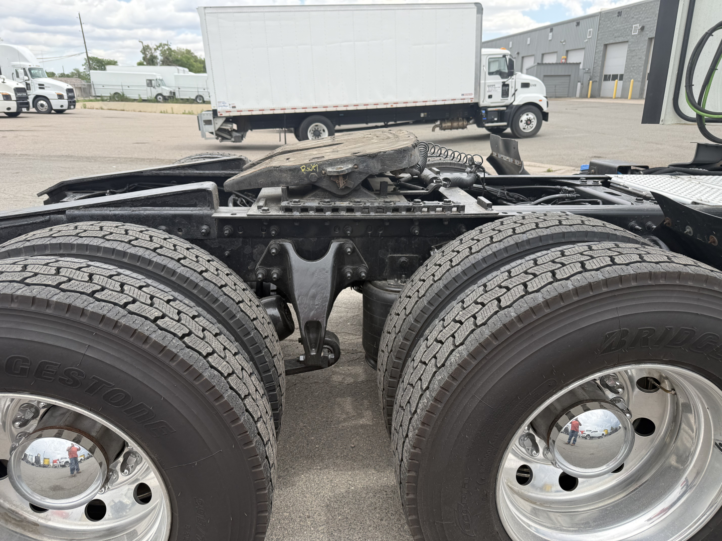 Two rear axles of a semi truck chassis with Bridgestone tires and chrome wheels, showing the tandem axle area and fifth wheel mounting surface.