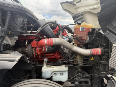 International LT625 engine bay showing red engine, hoses, coolant reservoir, and white washer reservoir.