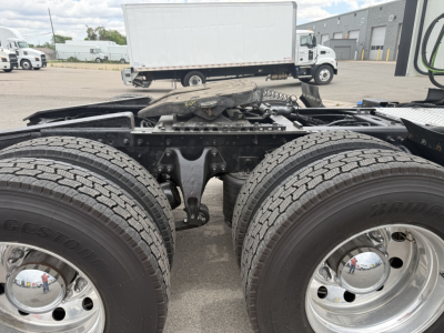 Two rear axles of a semi truck chassis with Bridgestone tires and chrome wheels, showing the tandem axle area and fifth wheel mounting surface.