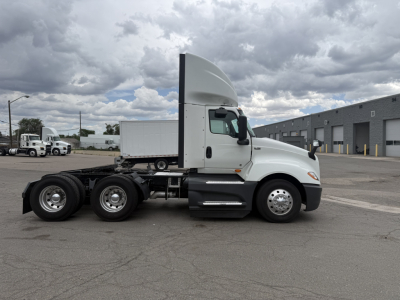 Tractor-trailer truck side view showing cab and dual rear axles, white exterior, International LT625, truck from used inventory.