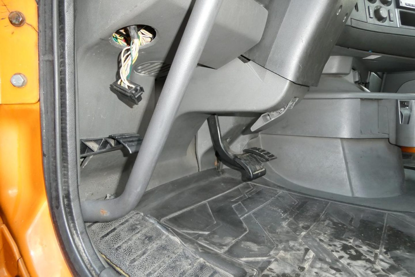 Volvo VNR cab interior view showing floor area near pedals and exposed wiring harness under dash.