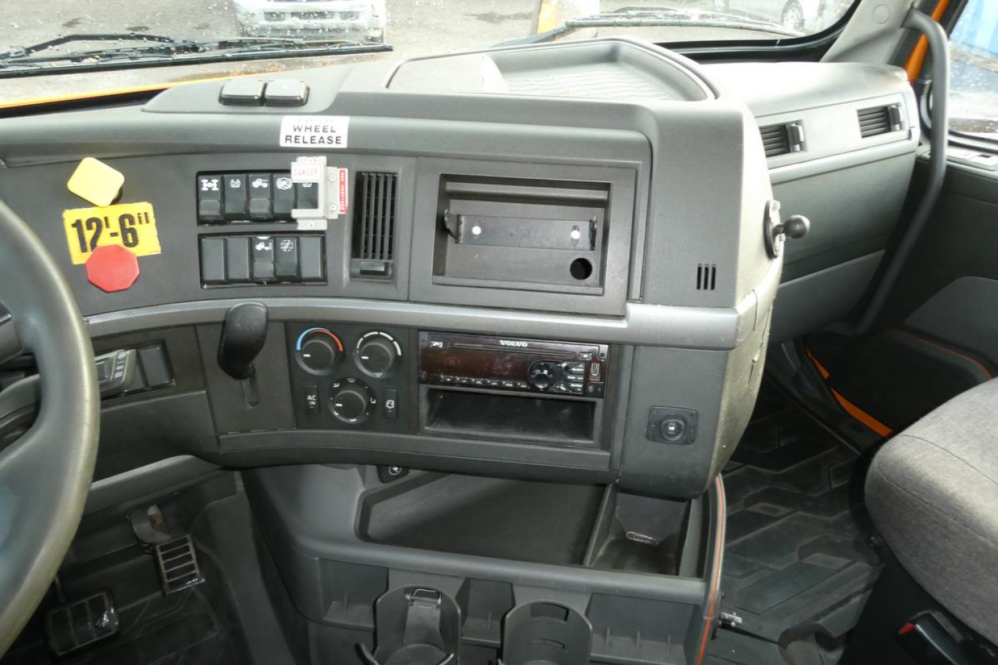 Dashboard view of a Volvo truck interior showing assorted controls, vents, and a blank radio slot.