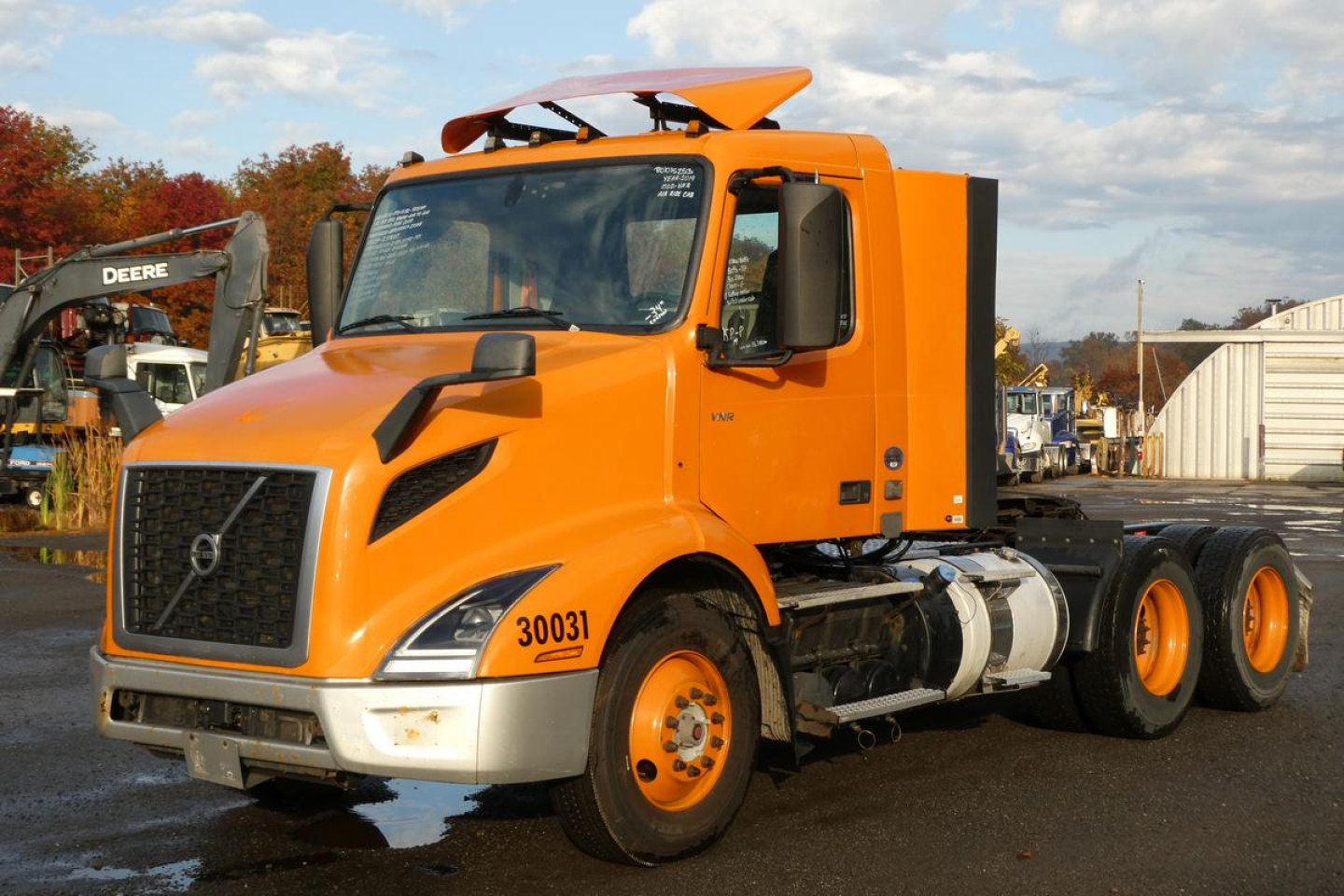 Orange Volvo VNR64T300 day cab tractor truck side view showing cab roof fairing and dual rear axles.