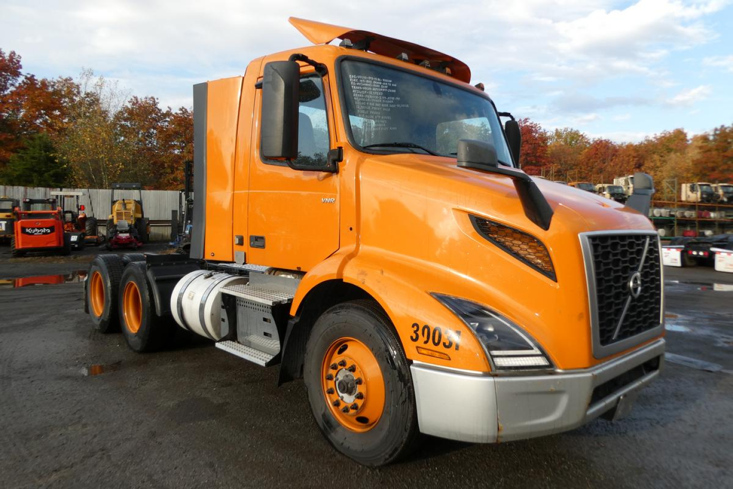 Volvo VNR64T300 day cab truck in orange with black grille and gray bumper, front three-quarter view showing headlights and cab features.