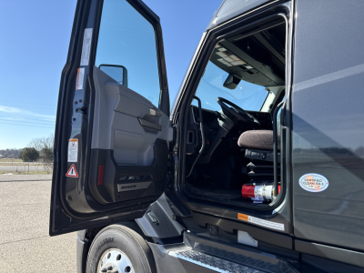 Truck cab door open showing Mack emblem on interior panel and dashboard area of a new 2026 Mack PR64T76H conventional sleeper truck.