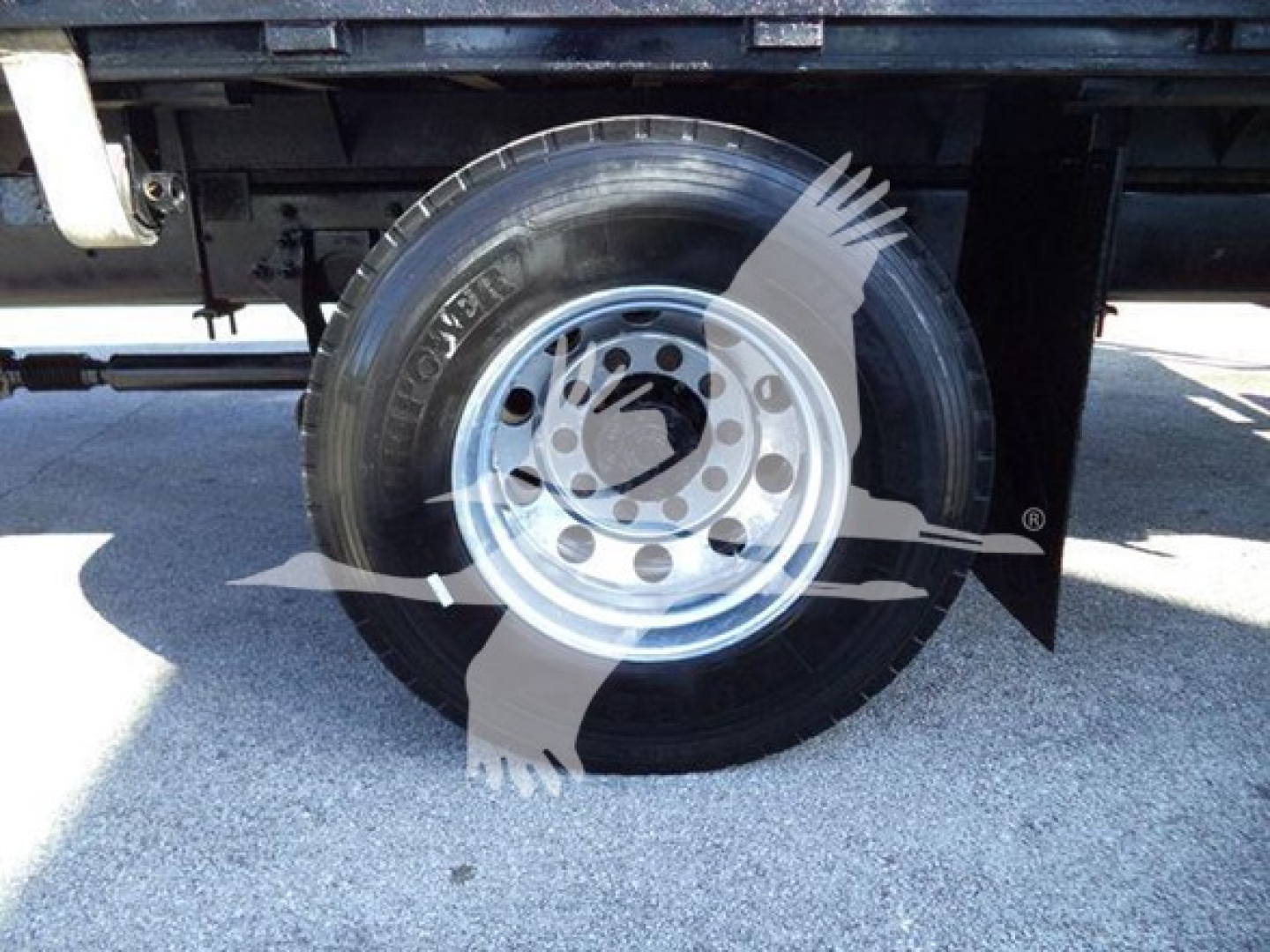 Wheel and tire of a flatbed truck showing Goodyear tire and metal rim.