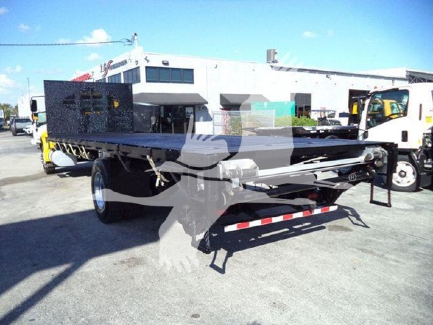 Flatbed truck trailer in yard showing 2019 International Durastar 4300 with flatbed cargo area and rear hitch.