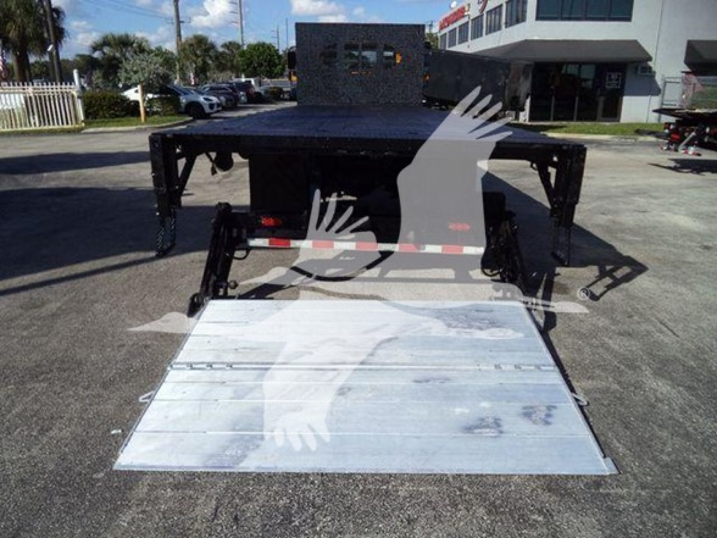 Flatbed truck with aluminum ramp lowered, rear view showing tail setup and platform; no legible serials or model numbers visible in this view.