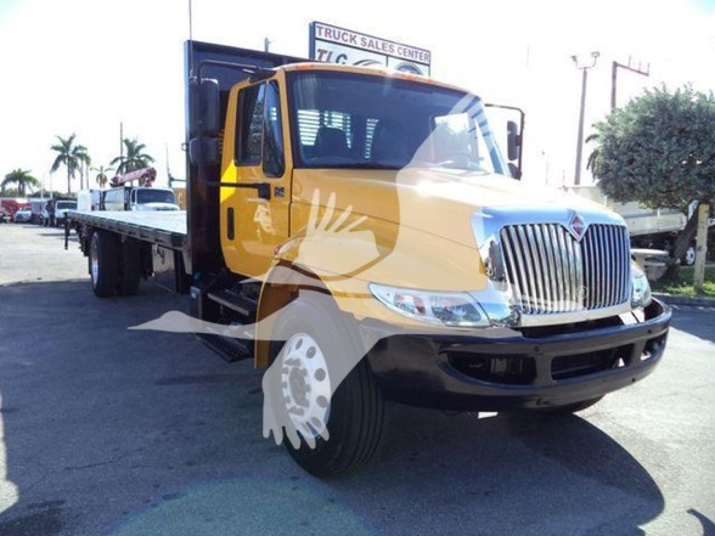 International Durastar 4300 flatbed truck showing front grille with chrome, yellow cab, black bumper, and flatbed in background.