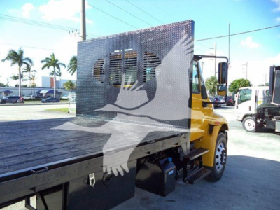 Truck bed with a yellow International Durastar 4300 flatbed and a perforated metal cab panel visible, side step, and front wheel in view.