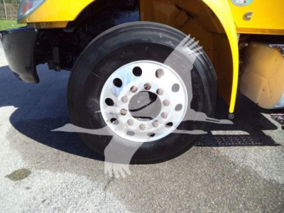 Truck wheel and front fender of a yellow 2019 International Durastar 4300 flatbed truck showing the front tire with polished rim.