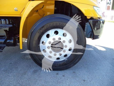 Wheel and front fender of a yellow International Durastar 4300 flatbed truck showing front tire and wheel well.