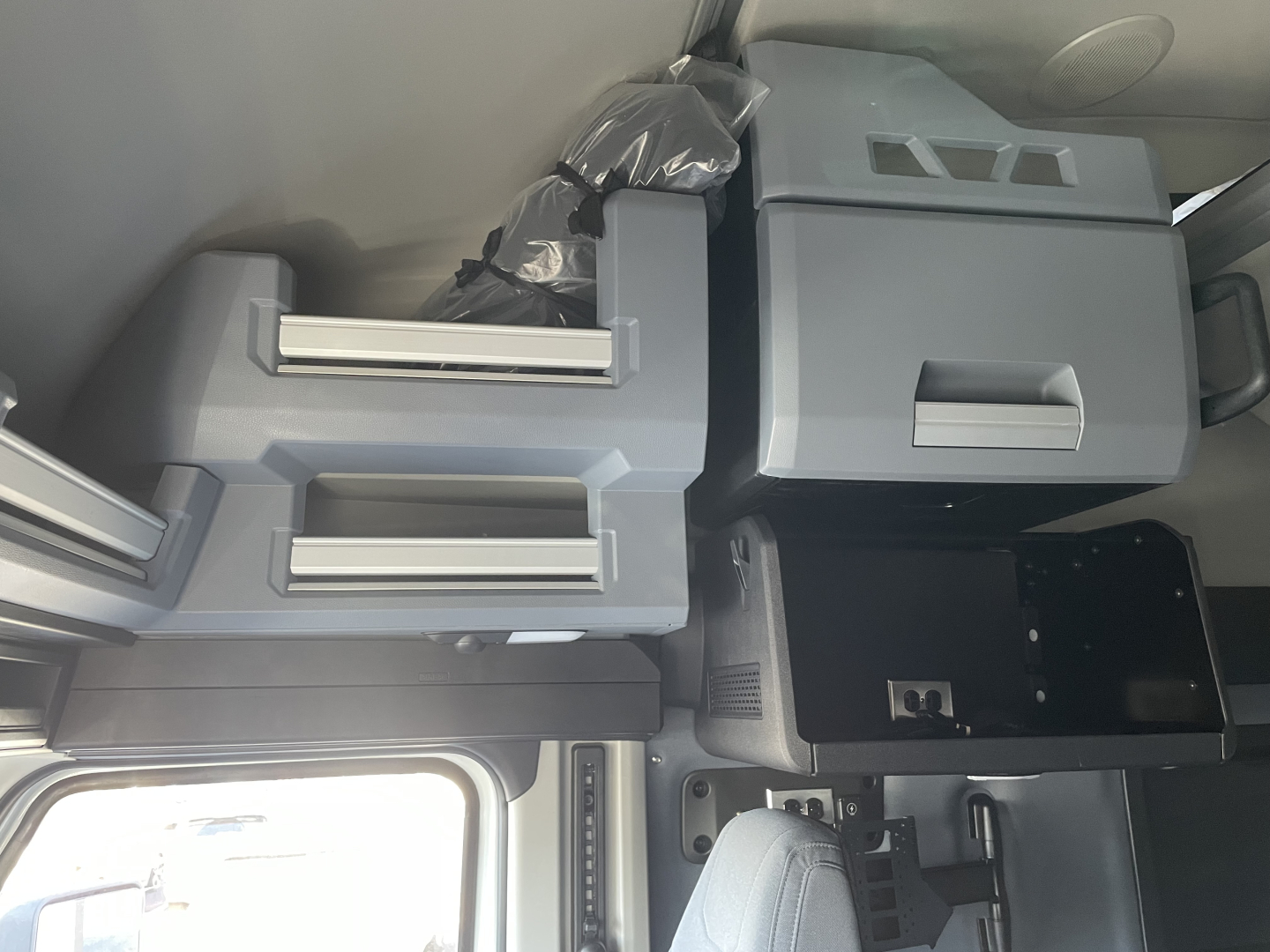 Truck cab interior showing storage compartments, electrical inverter, and overhead cabinets.