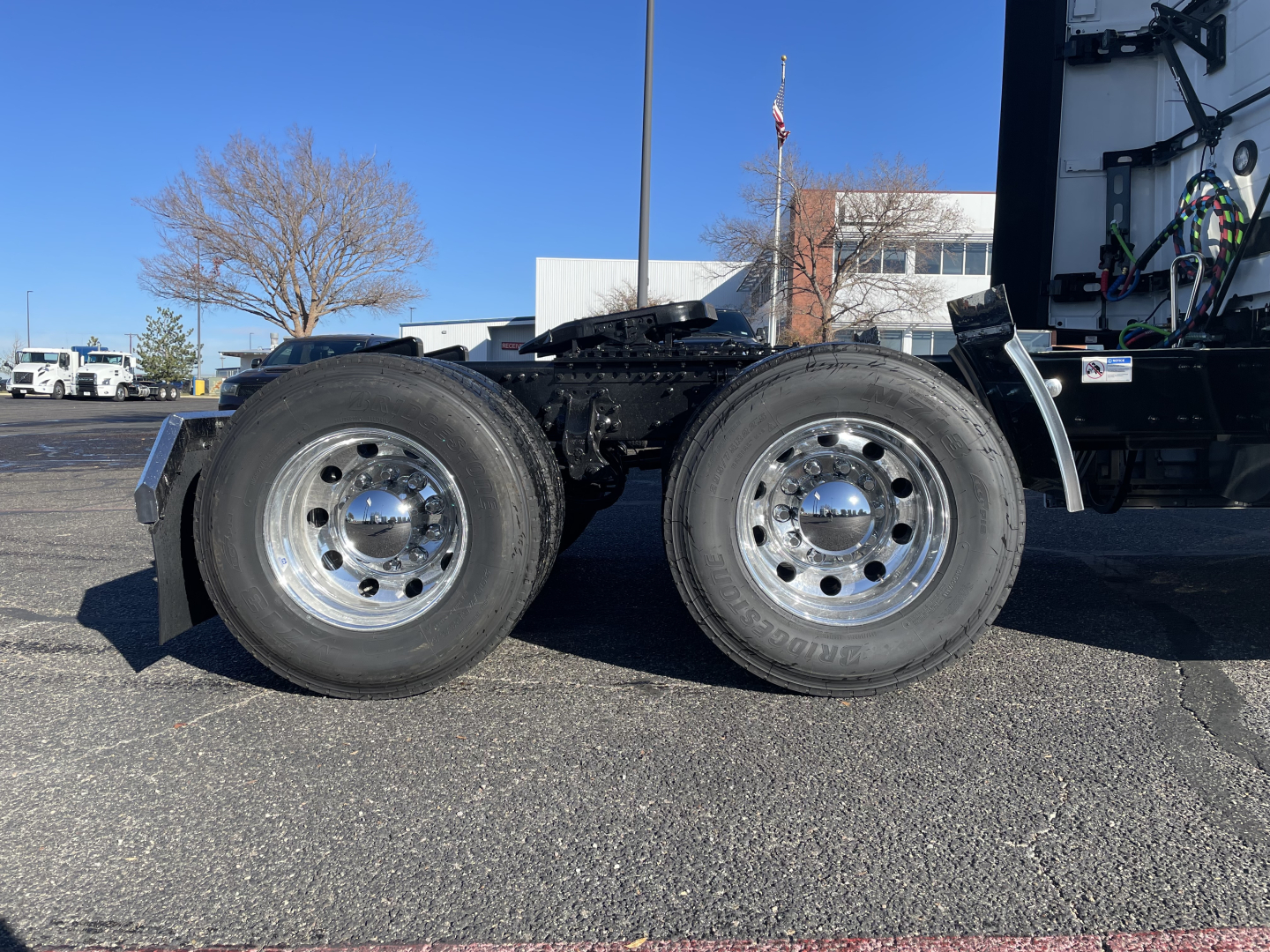 Truck rear view showing dual rear axles and tires on a Mack PR64T76H chassis with chrome wheels and chassis components visible.