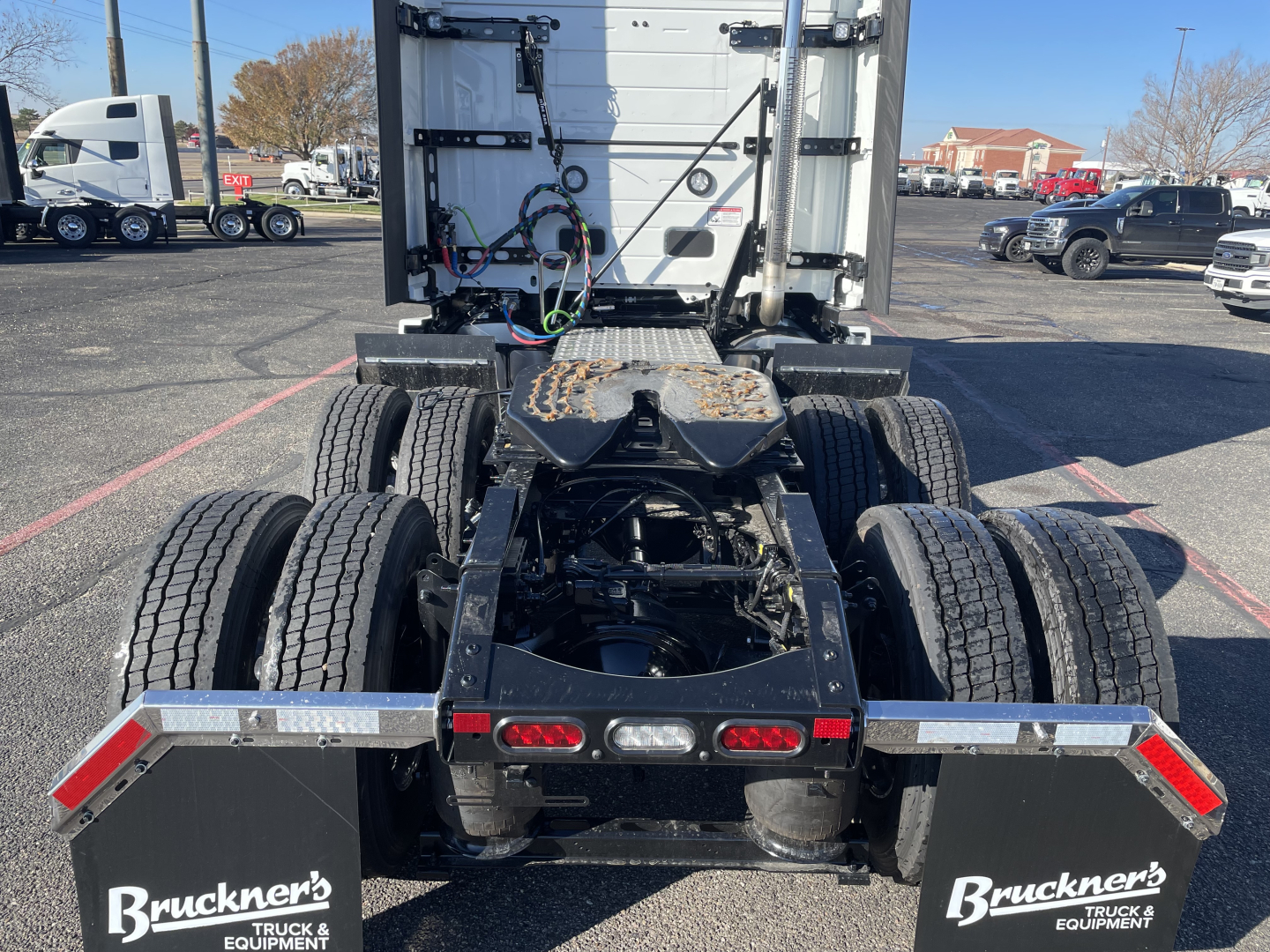Truck chassis of a new 2026 Mack PR64T76H viewed from rear showing dual rear axles, fifth wheel, and rear underrun protection with taillights; Bruckner's Truck Equipment branding on bumper.