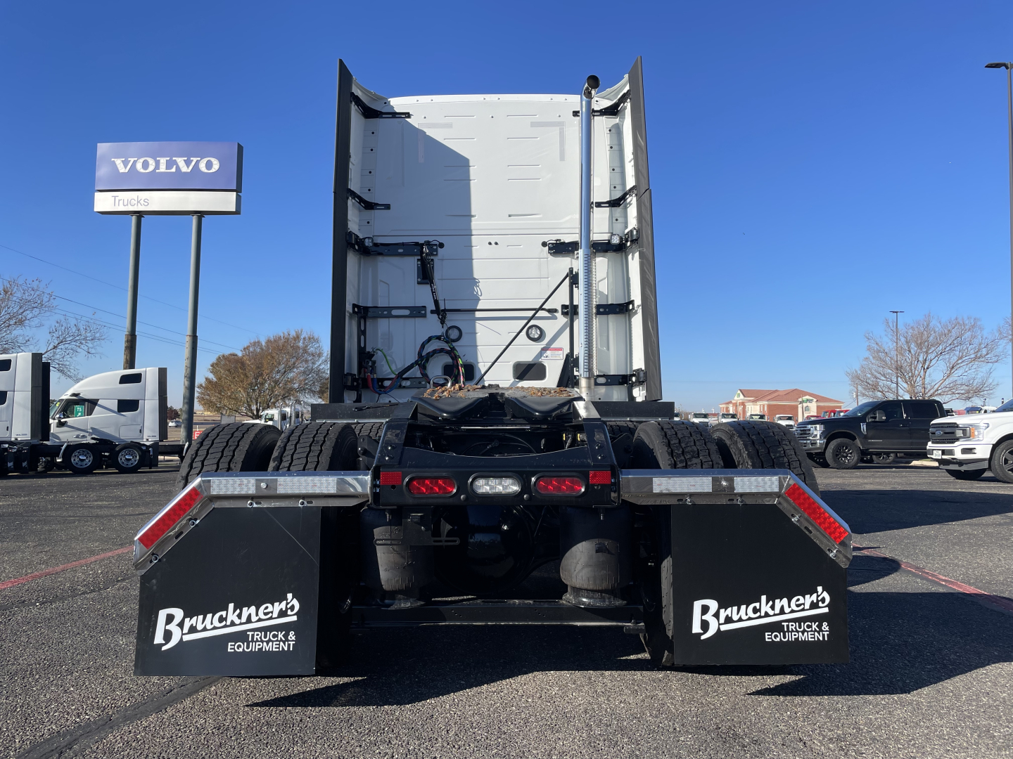Mack PR64T76H tractor with empty dump bed viewed from rear showing mud flaps with Bruckner's Truck & Equipment logos.