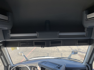Cab interior view of a new Mack PR64T76H sleeper truck showing dash area and windshield, with side mirrors and overhead storage panels.