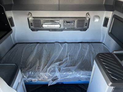 Mack PR64T76H truck interior sleeper cab cargo area with control panel at headboard and plastic-covered mattress.
