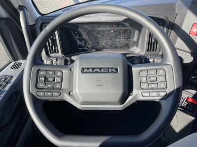 Mack PR64T76H truck steering wheel and dashboard with control buttons visible.