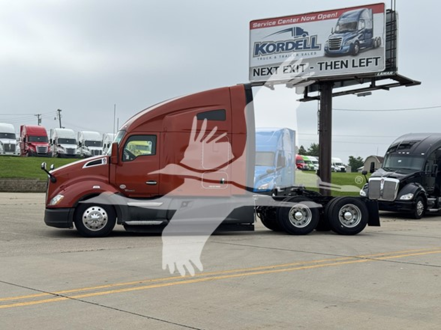 2019 Kenworth T680 conventional sleeper truck side view with red cab and billboard sign in background.