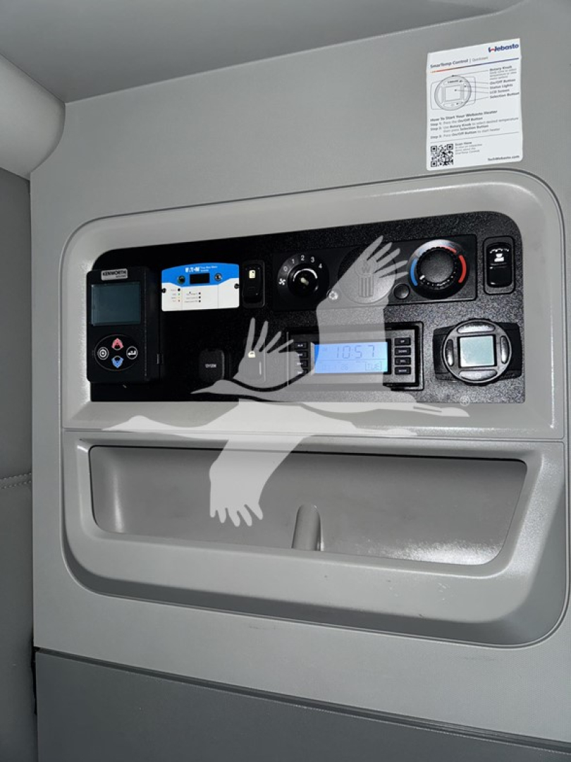 Dashboard panel in Kenworth T680 cab showing various controls and a digital display.