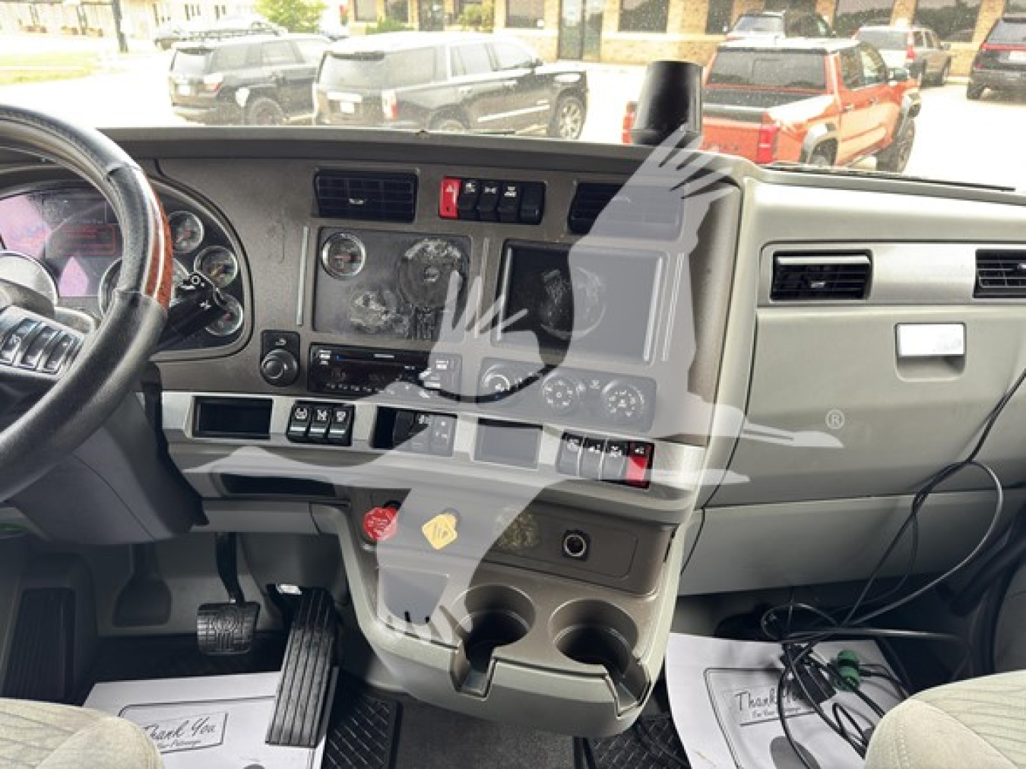 Truck dashboard interior showing steering wheel, control panel, center console with cup holders and switches.