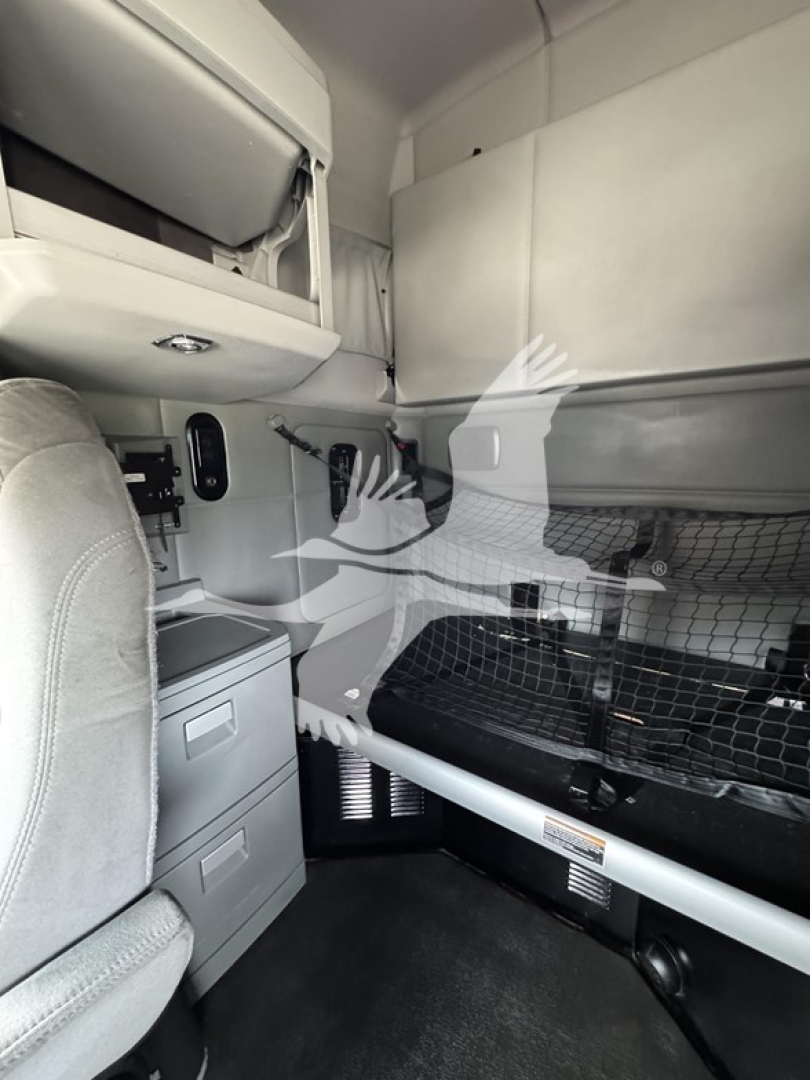 Cab interior of a 2019 Kenworth T680 sleeper showing bunk area, storage drawers, and overhead compartments.