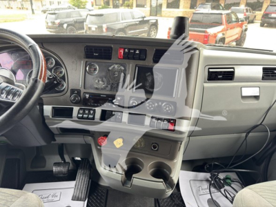 Truck dashboard interior showing steering wheel, control panel, center console with cup holders and switches.