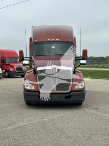 Kenworth T680 front view showing large chrome grille, headlights, and hood with mirrors. Vehicle appears in a parking lot.