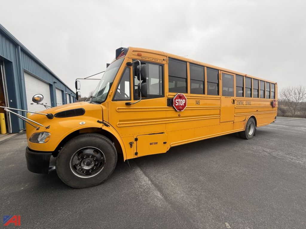 School bus side view showing orange body, stop sign, and passenger windows.