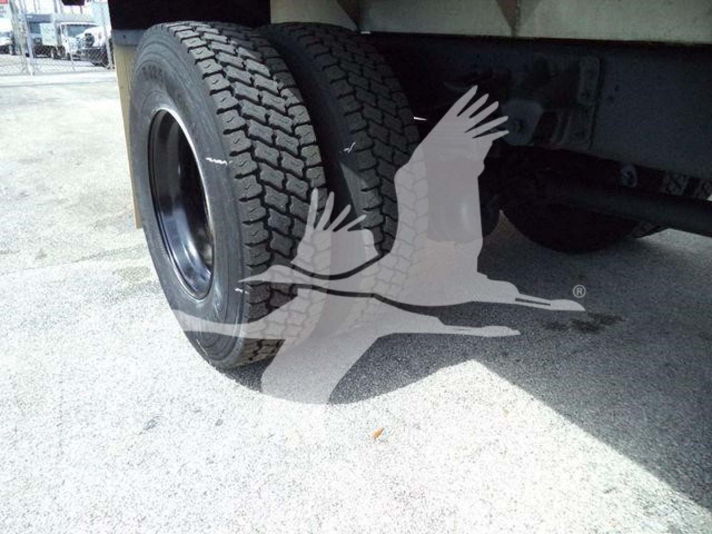 Isuzu truck undercarriage with dual rear tires and chassis visible.