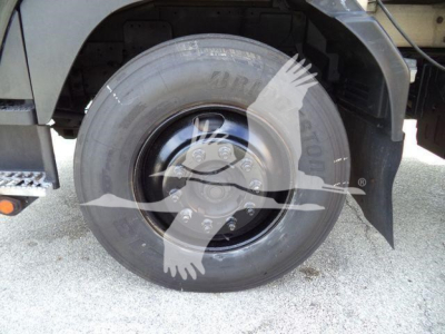 Isuzu truck wheel and fender view showing tire, rim, and mud flap.