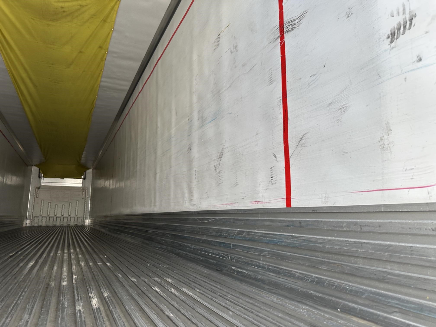 2015 Utility 3000R trailer interior view showing ribbed metal floor and side wall with yellow ceiling tarp.
