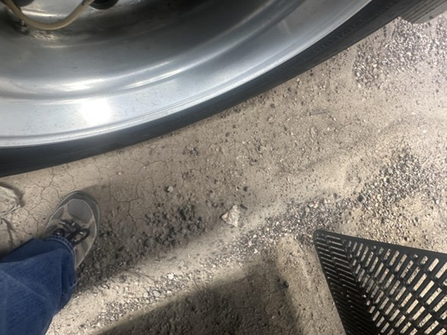 Wheel and fender area of a 2015 Utility 3000R trailer showing rim, tire, and ground with a boot or shoe in frame