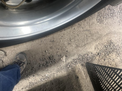 Wheel and fender area of a 2015 Utility 3000R trailer showing rim, tire, and ground with a boot or shoe in frame