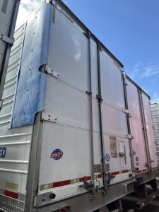 Utility 3000R trailer rear showing metal doors and hardware with Utility logo and warning stickers.