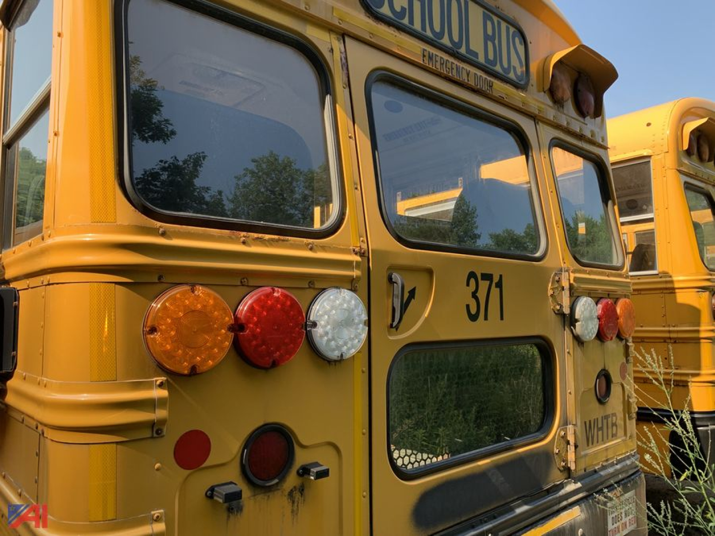 Yellow school bus rear view with number 371, multiple lights, back window, and ‘SCHOOL BUS’ sign partially visible.