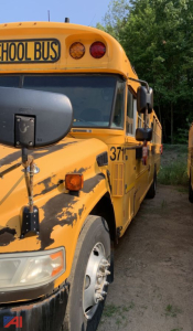 Bus front quarter showing yellow school bus with damage on hood and side, partial front wheel, and side door; numbers 37 and 'SCHOOL BUS' sign visible