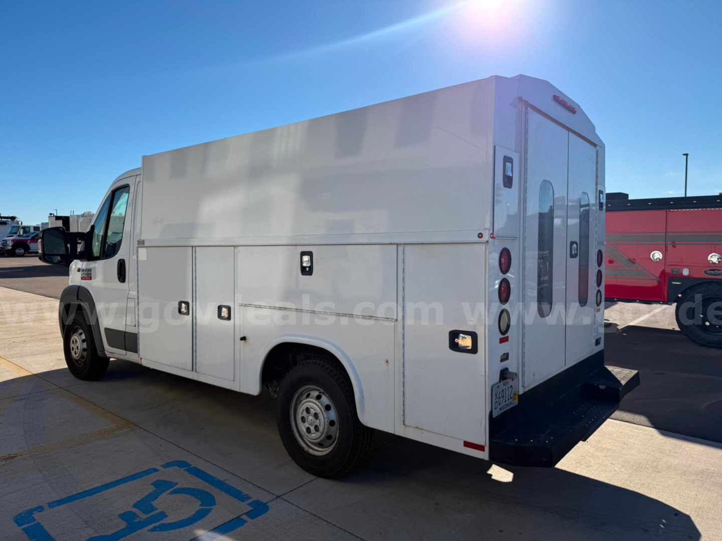 Ram ProMaster service utility box truck with large white cargo box and rear doors, side compartments, parked on pavement in a dealership lot.