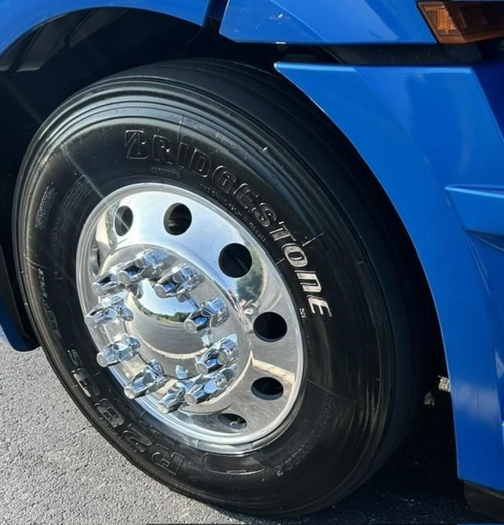 Bridgestone tire and chrome wheel on a blue Freightliner Cascadia truck, front left view.