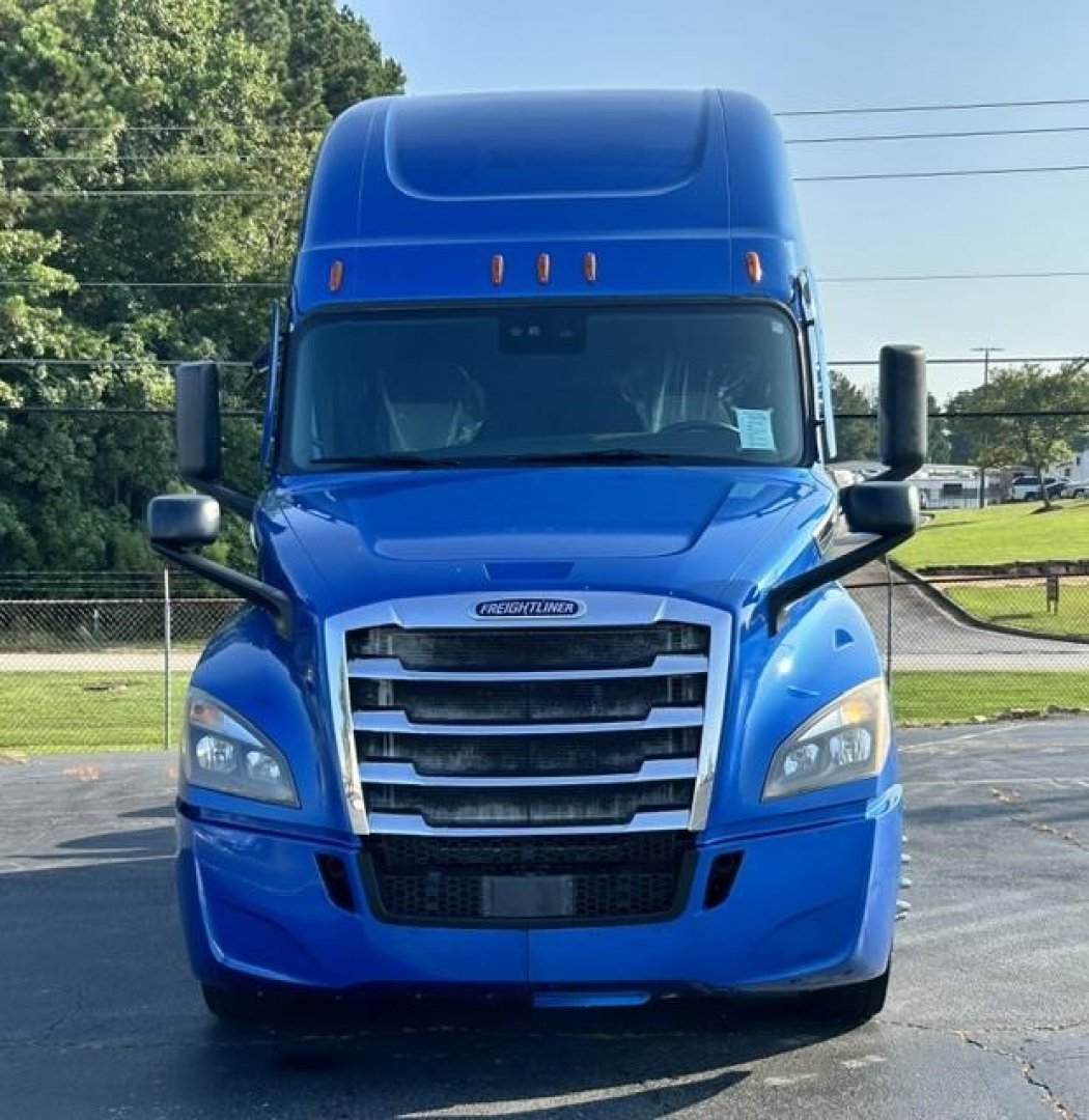 Front view of a blue Freightliner Cascadia 126 tractor-trailer cab with grille, headlights, and aerodynamic mirrors visible.